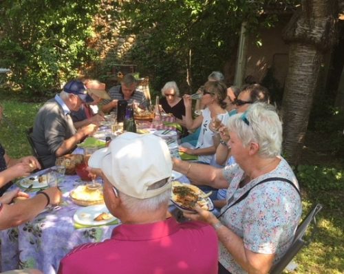 Gruppe sidder i en have og spiser picnic