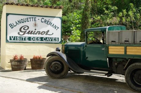 Billede af skilt uden for Guinot vineriet. En veteranbil med tomme vin kasser står i højre side